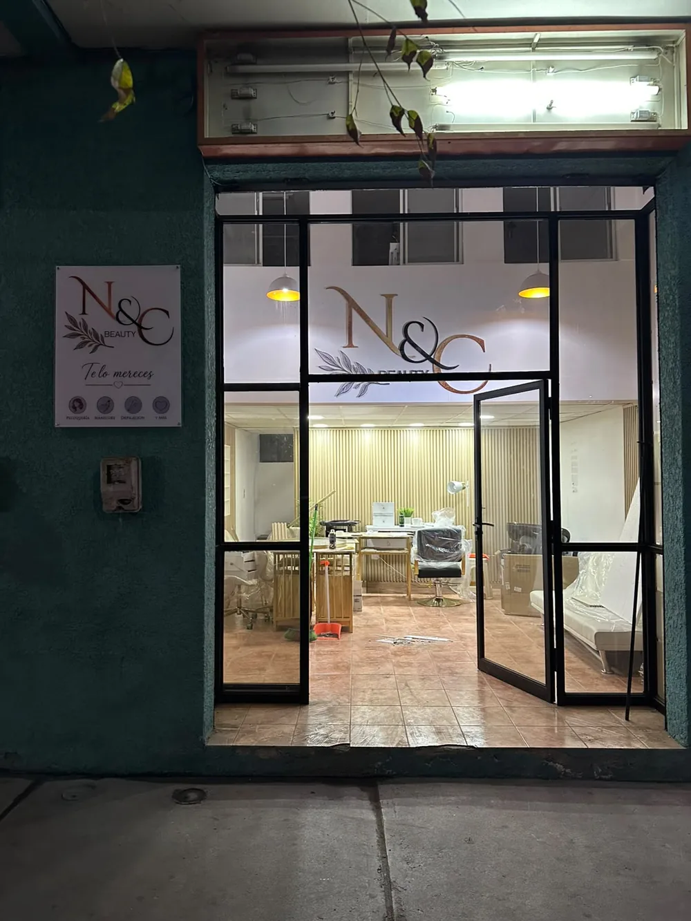 Fachada real de N&C Beauty de noche, con la vitrina iluminada